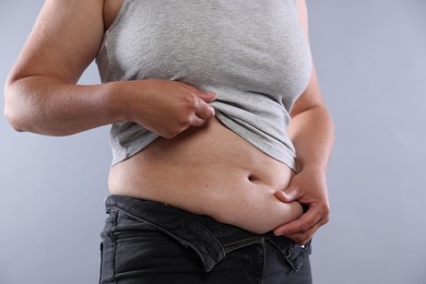 Photo of Woman with excessive belly fat on light background, closeup. Overweight problem