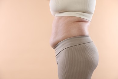 Photo of Woman with excessive belly fat on beige background, closeup and space for text. Overweight problem