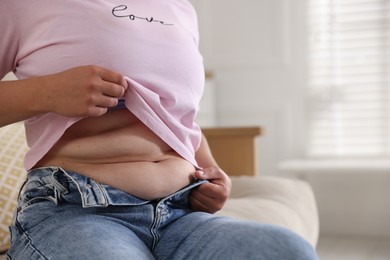 Photo of Woman with excessive belly fat at home, closeup and space for text. Overweight problem