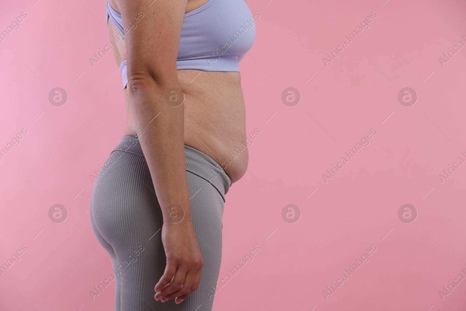 Woman with excessive belly fat on pink background, closeup and space for text. Overweight problem Photo of Woman with excessive belly fat on pink background, closeup and space for text. Overweight problem