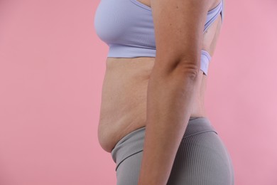Photo of Woman with excessive belly fat on pink background, closeup. Overweight problem