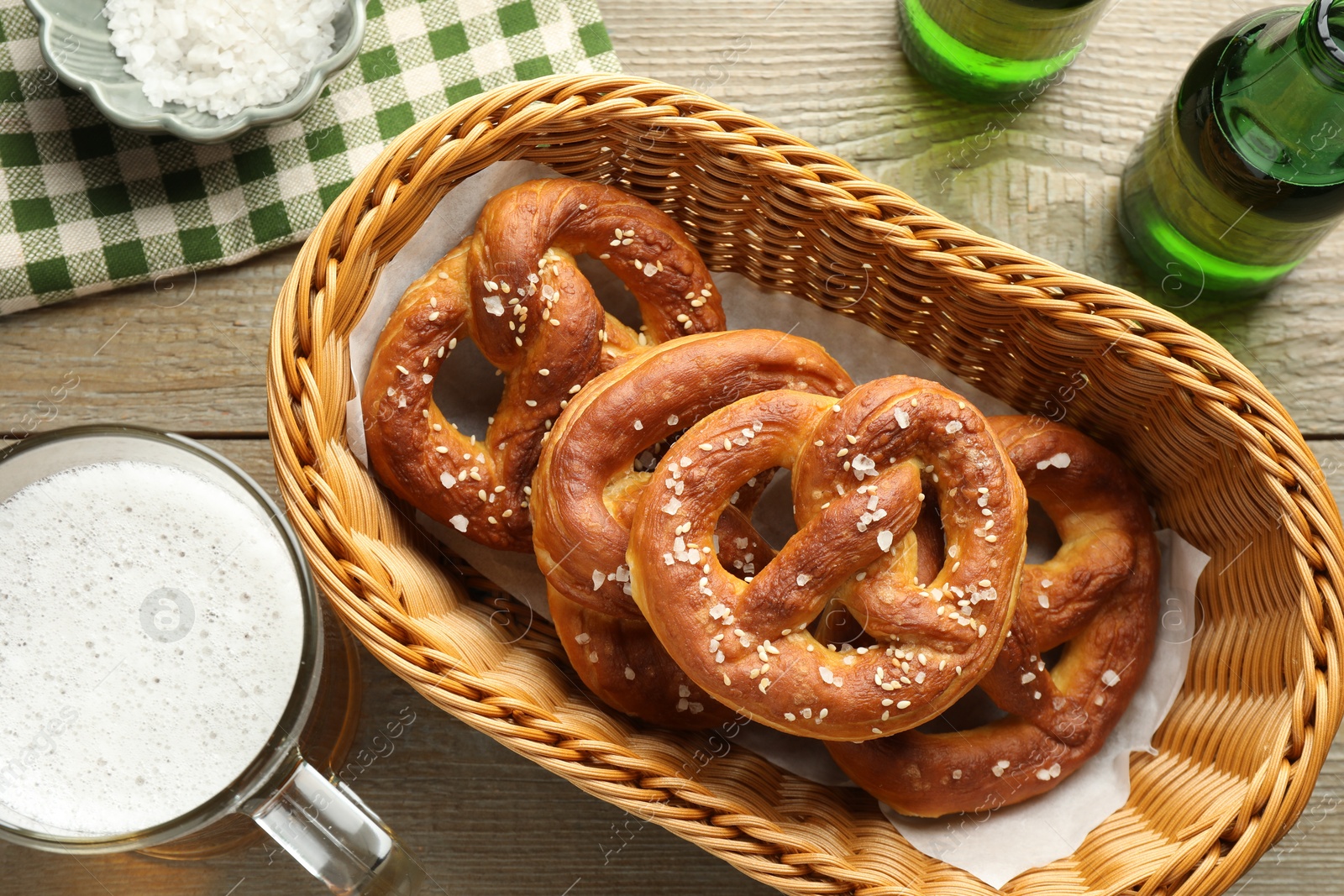 Tasty pretzels in basket and beer on wooden table, flat lay Photo of Tasty pretzels in basket and beer on wooden table, flat lay