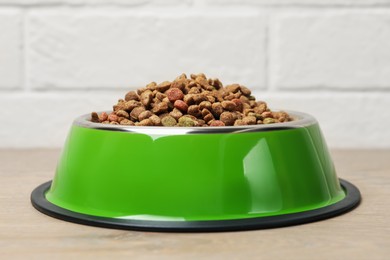 Photo of Dry pet food in feeding bowl on floor, closeup