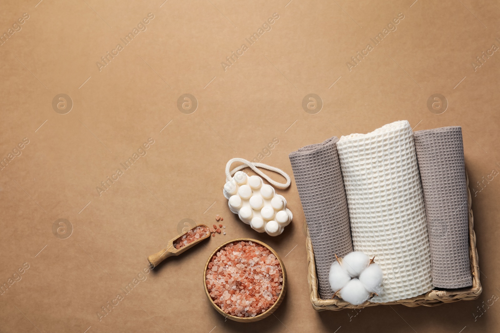 Clean waffle towels and cosmetic products on brown background, flat lay. Space for text Photo of Clean waffle towels and cosmetic products on brown background, flat lay. Space for text