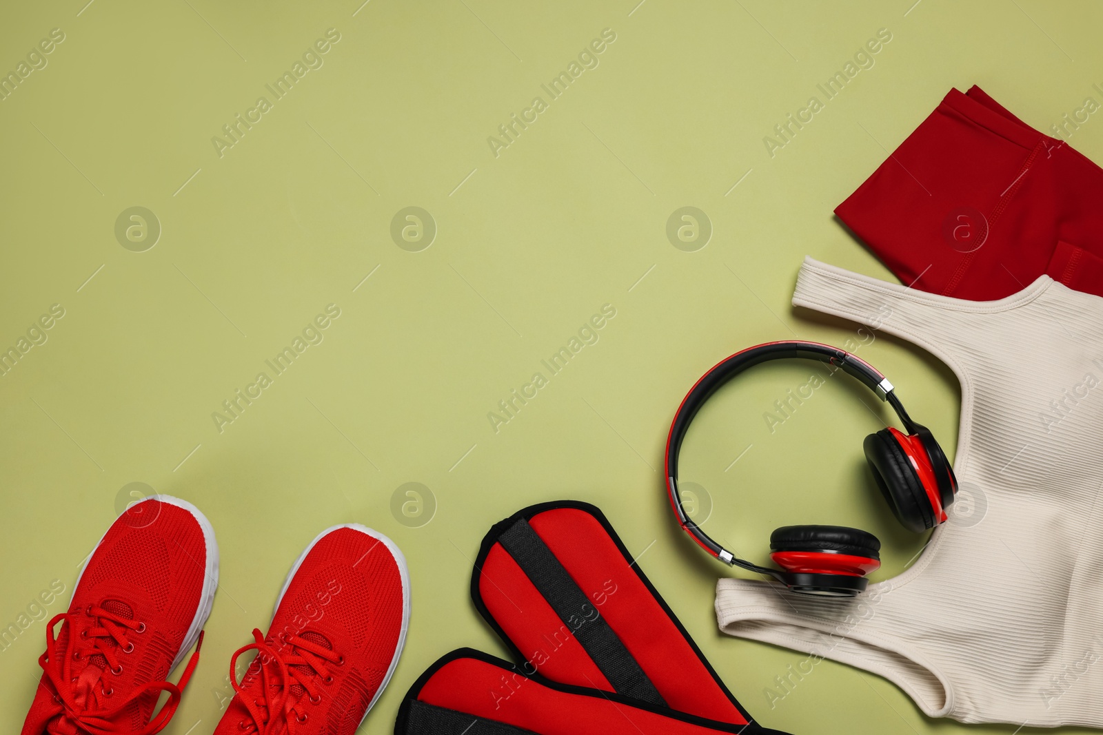 Sportswear, sneakers, headphones and ankle weights on pale olive background, flat lay. Space for text Photo of Sportswear, sneakers, headphones and ankle weights on pale olive background, flat lay. Space for text