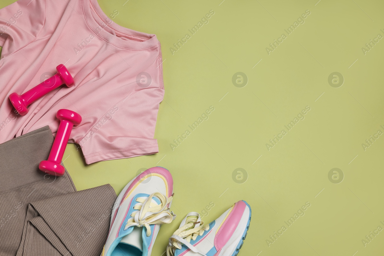 Sportswear, sneakers and dumbbells on pale olive background, flat lay. Space for text Photo of Sportswear, sneakers and dumbbells on pale olive background, flat lay. Space for text