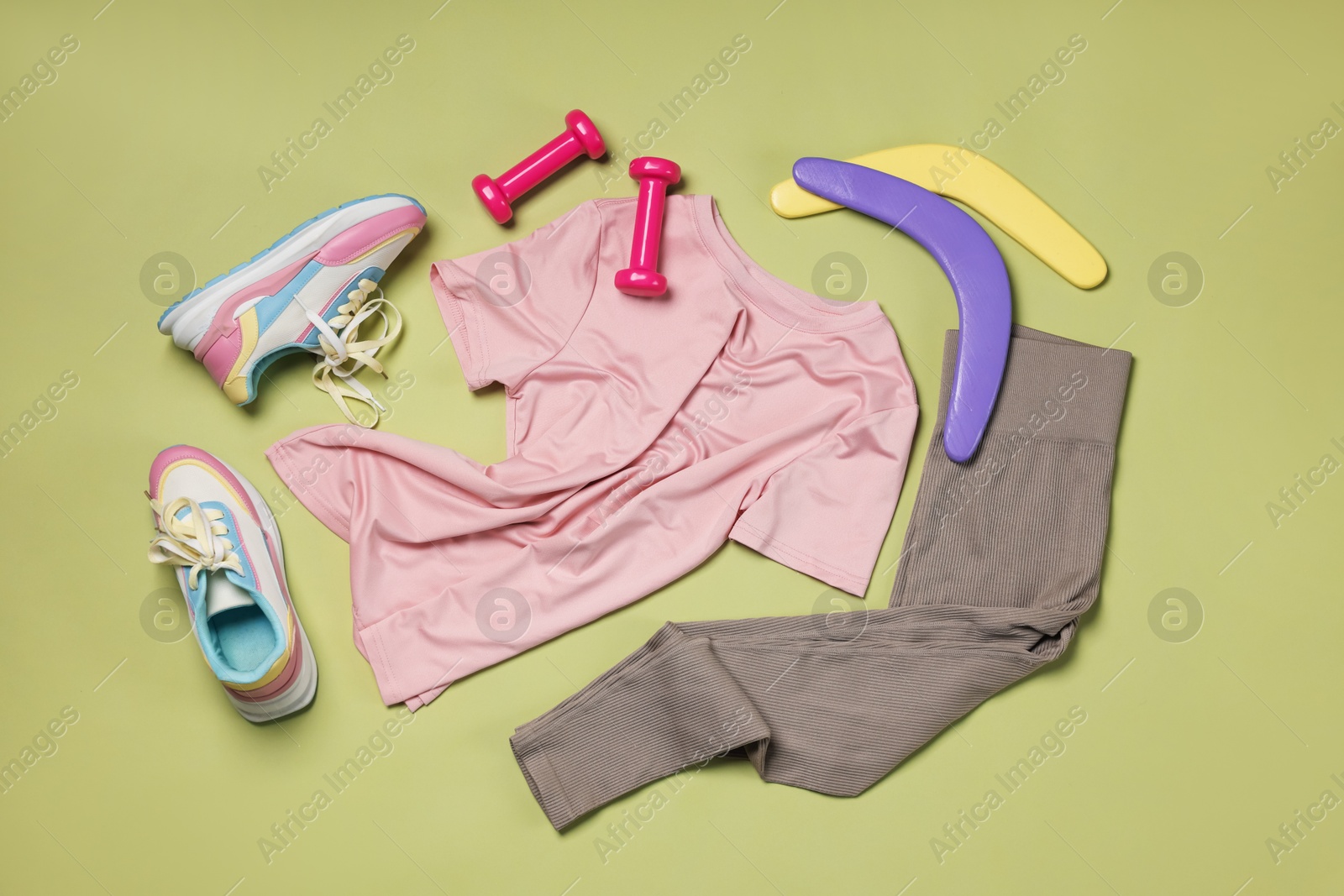 Sportswear, sneakers, dumbbells and boomerangs on pale olive background, flat lay Photo of Sportswear, sneakers, dumbbells and boomerangs on pale olive background, flat lay