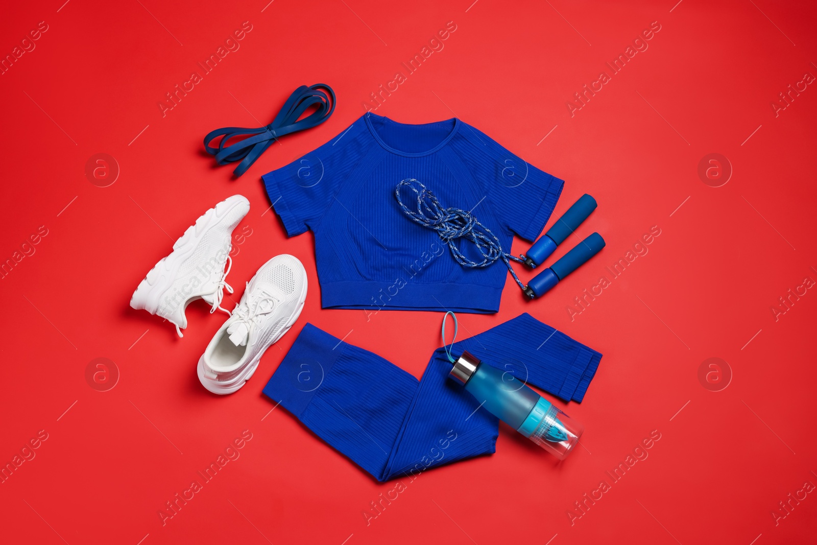 Sportswear, sneakers, skipping rope and water bottle on red background, flat lay Photo of Sportswear, sneakers, skipping rope and water bottle on red background, flat lay