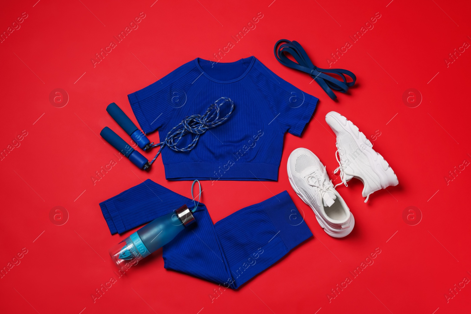 Sportswear, sneakers, skipping rope and water bottle on red background, flat lay Photo of Sportswear, sneakers, skipping rope and water bottle on red background, flat lay