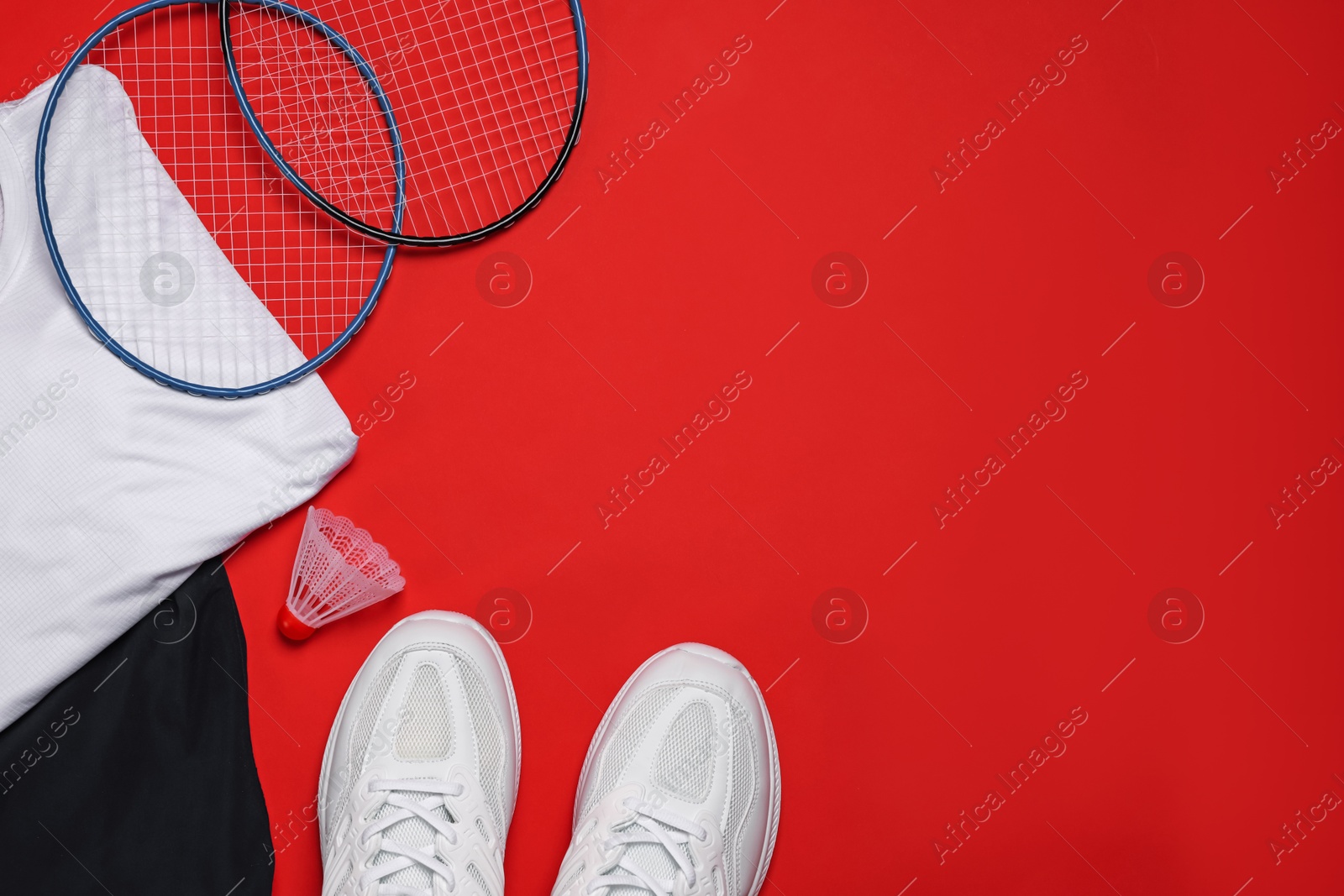 Sportswear, sneakers, badminton rackets and shuttlecock on red background, flat lay. Space for text Photo of Sportswear, sneakers, badminton rackets and shuttlecock on red background, flat lay. Space for text