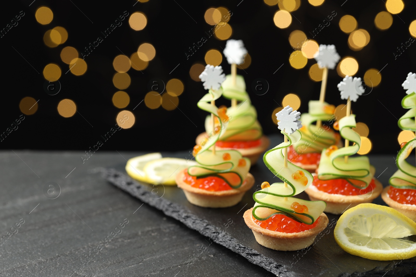 Photo of Tasty canapes on black table against dark background with blurred lights, space for text. Bokeh effect