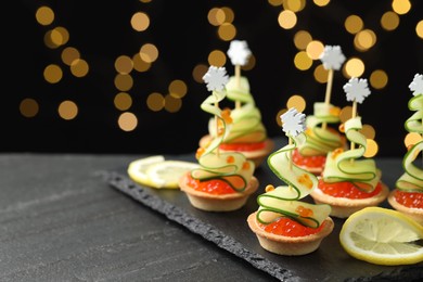 Photo of Tasty canapes on black table against dark background with blurred lights, space for text. Bokeh effect