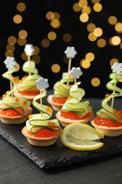 Photo of Tasty canapes on black table against dark background with blurred lights, closeup. Bokeh effect