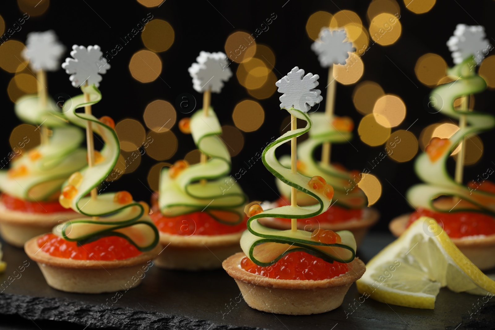 Photo of Tasty canapes on table against dark background with blurred lights, closeup. Bokeh effect