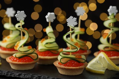 Photo of Tasty canapes on table against dark background with blurred lights, closeup. Bokeh effect