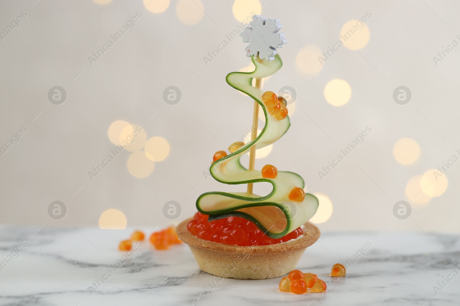 Photo of Tasty canape on white marble table against background with blurred lights, closeup. Bokeh effect