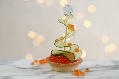 Photo of Tasty canape on white marble table against background with blurred lights, closeup. Bokeh effect