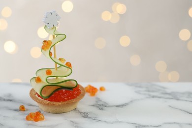 Photo of Tasty canape on white marble table against background with blurred lights, space for text. Bokeh effect
