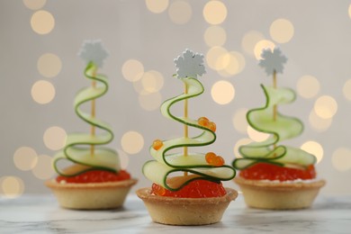 Photo of Tasty canapes on white marble table against background with blurred lights, closeup. Bokeh effect