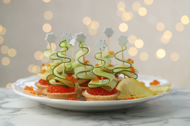 Photo of Tasty canapes on white marble table against background with blurred lights, closeup. Bokeh effect