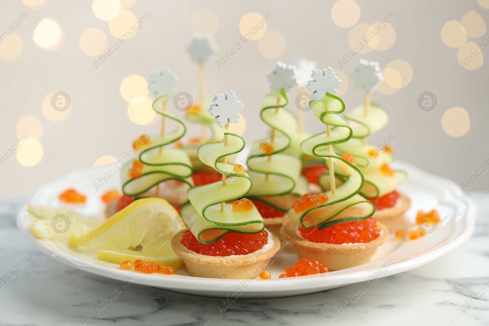 Photo of Tasty canapes on white marble table against background with blurred lights, closeup. Bokeh effect