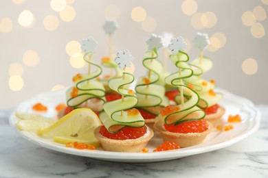 Photo of Tasty canapes on white marble table against background with blurred lights, closeup. Bokeh effect