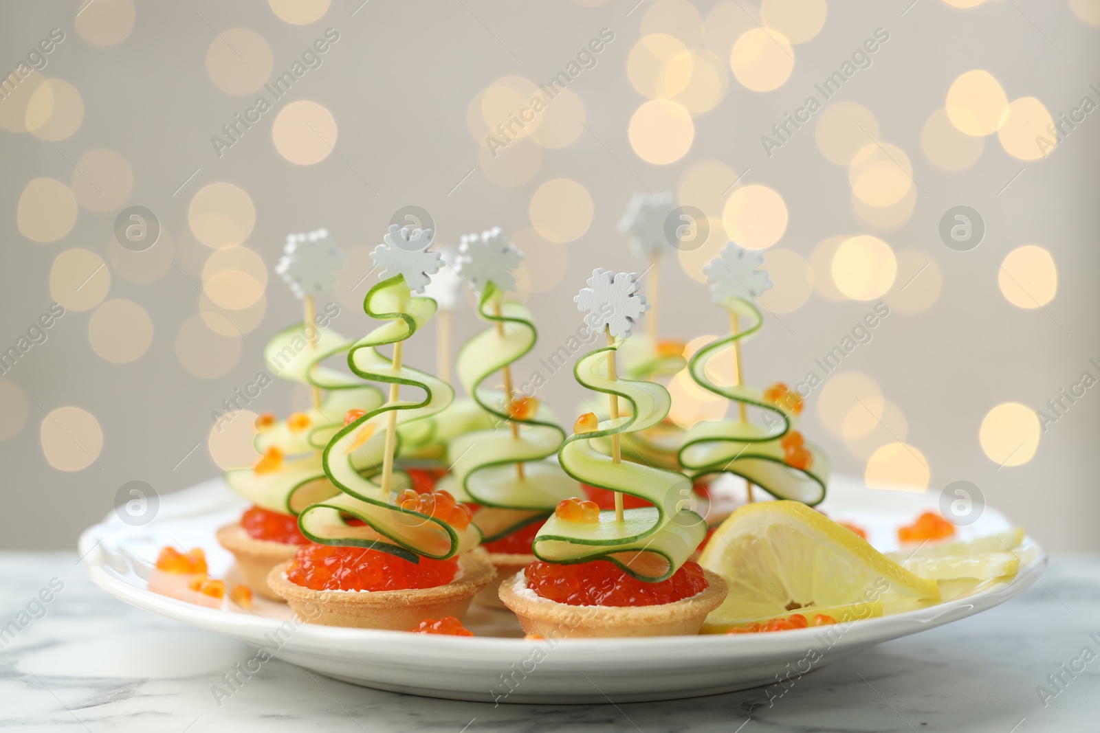 Photo of Tasty canapes on white marble table against background with blurred lights, closeup. Bokeh effect