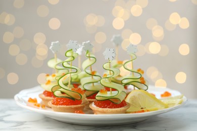 Photo of Tasty canapes on white marble table against background with blurred lights, closeup. Bokeh effect
