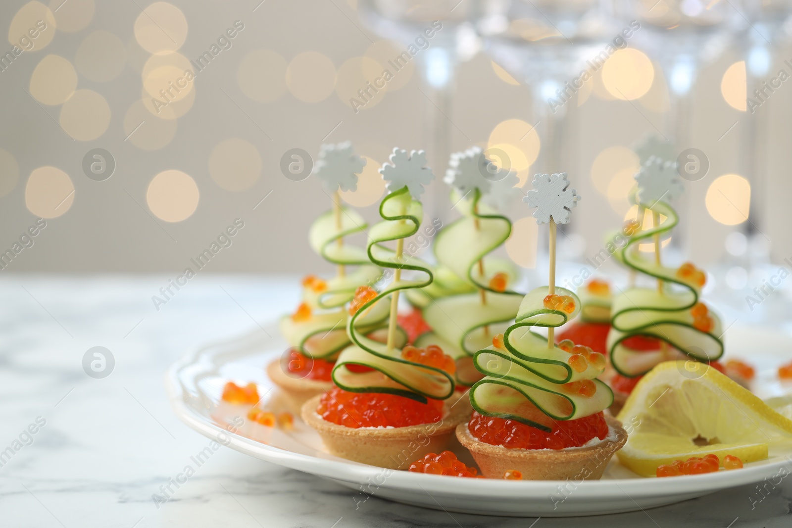 Photo of Tasty canapes on white marble table against background with blurred lights, space for text. Bokeh effect
