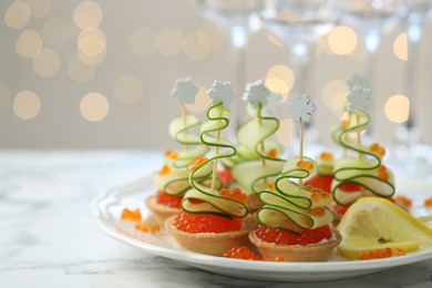 Photo of Tasty canapes on white marble table against background with blurred lights, space for text. Bokeh effect