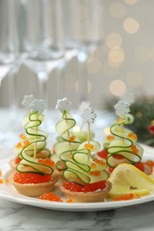 Photo of Tasty canapes on white marble table against background with blurred lights, closeup. Bokeh effect