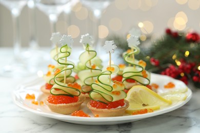 Photo of Tasty canapes and Christmas decor on white marble table, closeup. Bokeh effect