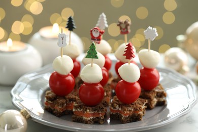 Photo of Tasty canapes and Christmas decor on table against background with blurred lights, closeup. Bokeh effect