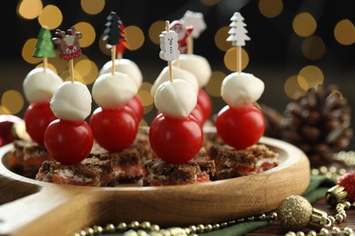 Photo of Tasty canapes and Christmas decor on table against background with blurred lights, closeup. Bokeh effect