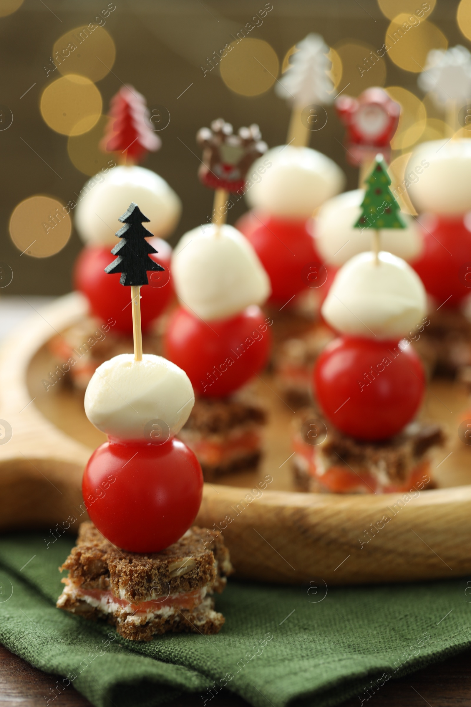 Photo of Tasty canapes on table against background with blurred lights, closeup. Bokeh effect