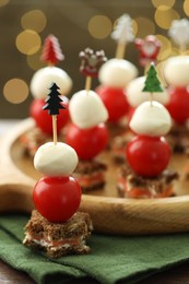 Photo of Tasty canapes on table against background with blurred lights, closeup. Bokeh effect