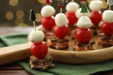 Photo of Tasty canapes on wooden table against background with blurred lights, closeup. Bokeh effect