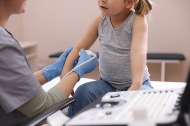 Photo of Sonographer conducting ultrasound examination of little girl's arm in clinic, closeup