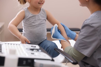 Photo of Sonographer conducting ultrasound examination of little girl's arm in clinic, closeup