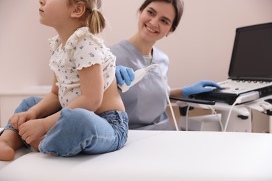 Photo of Sonographer conducting little girl's renal ultrasound examination in clinic, closeup
