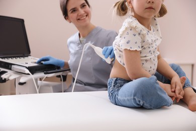 Photo of Sonographer conducting little girl's renal ultrasound examination in clinic, closeup