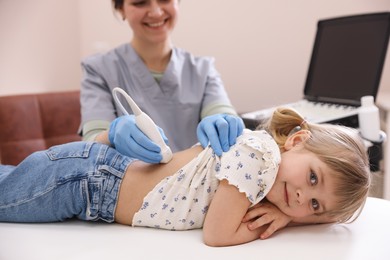 Photo of Sonographer conducting little girl's renal ultrasound examination in clinic, closeup