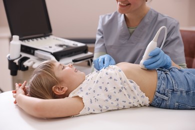 Photo of Sonographer conducting little girl's abdominal ultrasound examination in clinic, closeup