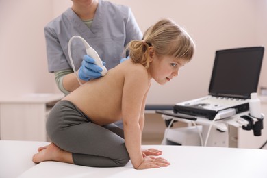 Photo of Sonographer conducting little girl's ultrasound examination in clinic, closeup