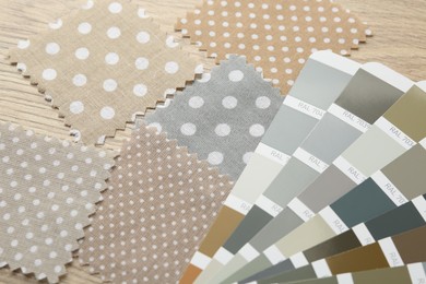 Photo of Samples of colorful fabrics and color palettes on wooden table, closeup