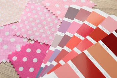 Photo of Samples of colorful fabrics and color palettes on wooden table, closeup