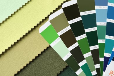 Photo of Samples of colorful fabrics and color palettes, top view