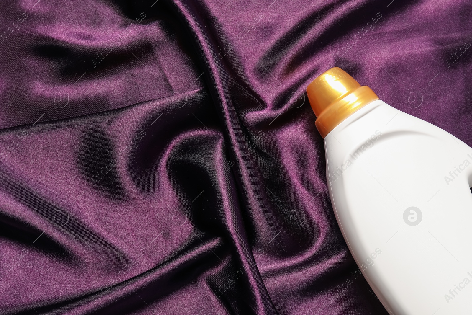 Bottle of fabric softener on purple cloth, top view. Space for text Photo of Bottle of fabric softener on purple cloth, top view. Space for text