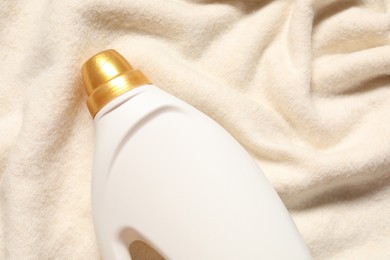 Photo of Bottle of fabric softener on soft cloth, top view