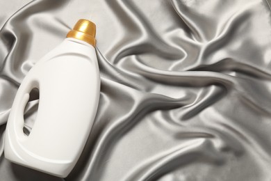 Photo of Bottle of fabric softener on grey cloth, top view. Space for text